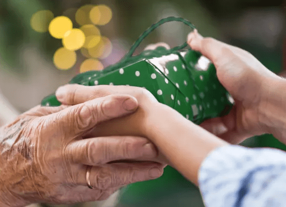 Person handing a green gift-wrapped present to another person