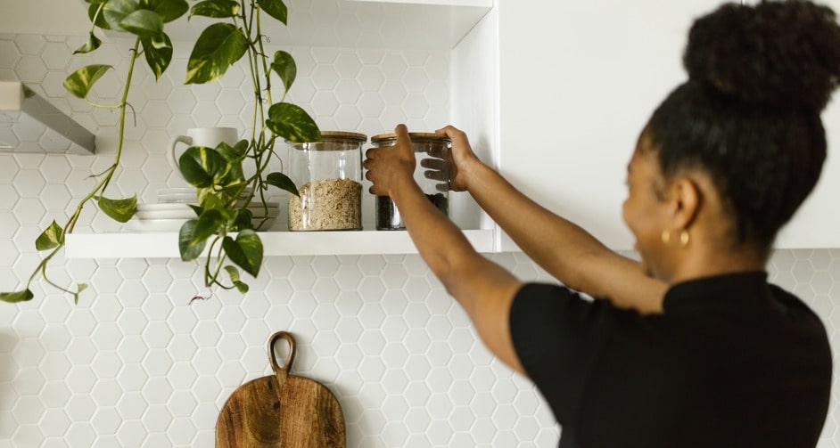 Woman arranging jars on kitchen shelf