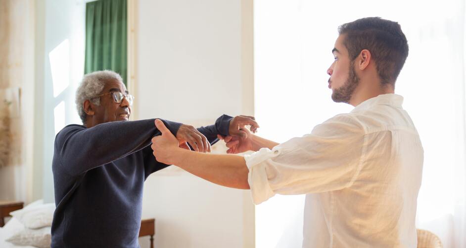 Male nurse helping older man exercise arms